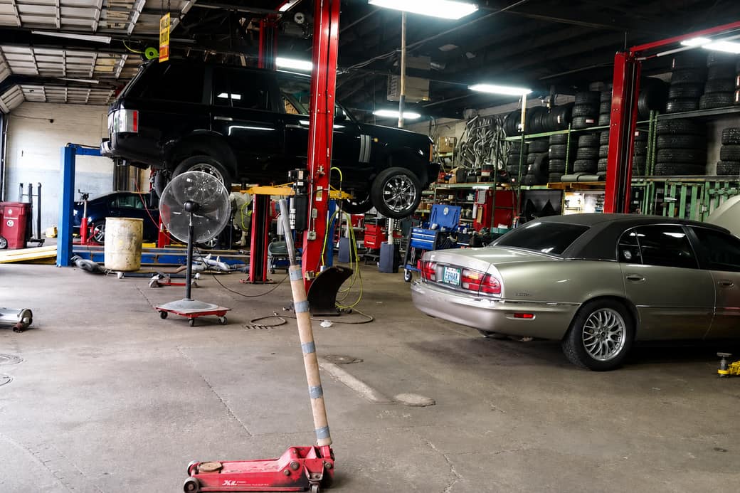 Wide view of the ERMAK Tires shop floor with vehicles on red lifts.